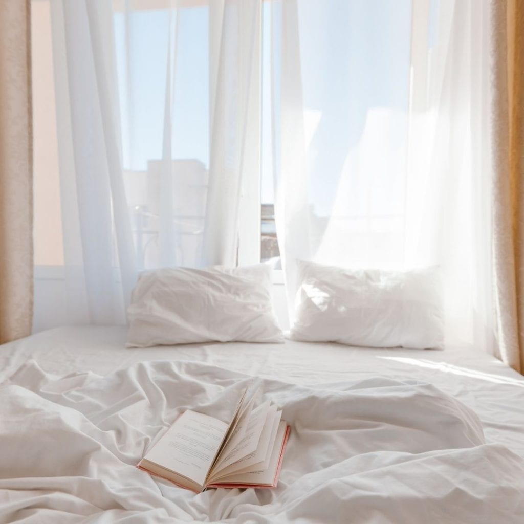 letto lenzuola bianche, libro, finestra aperta